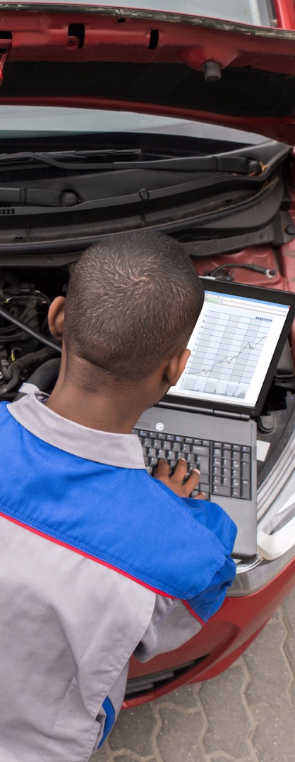 Mechanic Using Laptop To Run Diagnostic Checks On Car Engine